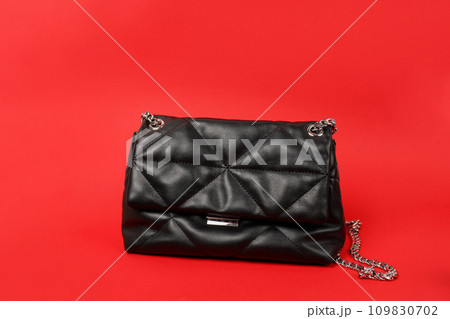 Black female handbag with chain on red background 109830702