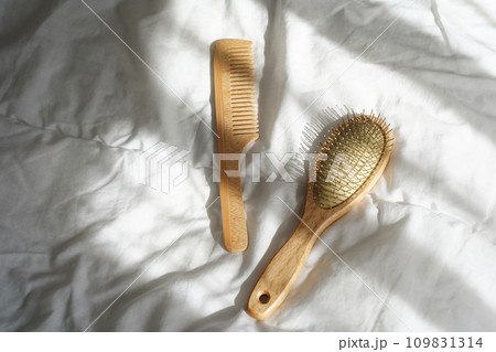 Wooden hairbrushes on white bed background with shadows from window Wooden hairbrushes on white bed background with shadows from window 109831314