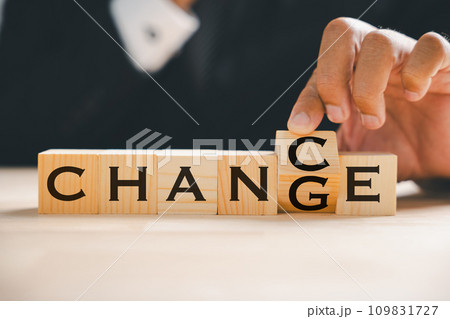 Wood block transforms, CHANGE to CHANCE, held by businessman. Success, strategy, and new opportunities embodied. Vintage table setting underscores transformation. Change is. 109831727