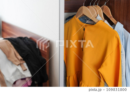 Brightly colored clothes on hangers in the closet. Decluttering the cabinet Brightly colored clothes on hangers in the closet. Decluttering the cabinet 109831800