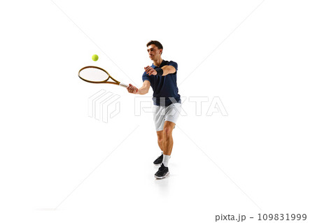 Competitive man in his 30s, tennis player in motion, hitting ball with racket, practicing isolated over white background 109831999
