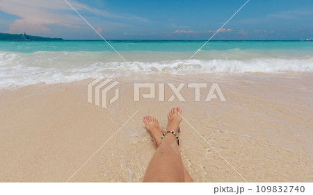 POV shot of two female feet relaxing on the beach on sunny day. A woman lying on the beach. Travel concept. Boracay, Philippines. 109832740