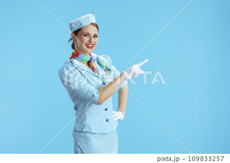 smiling stylish stewardess woman on blue pointing at something 109833257
