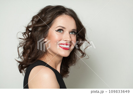 Smiling model woman with healthy wavy hairstyle looking up, studio fashion beauty portrait. 109833649