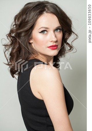 Attractive woman brunette with makeup and shiny wavy brown hair studio portrait. 109833650