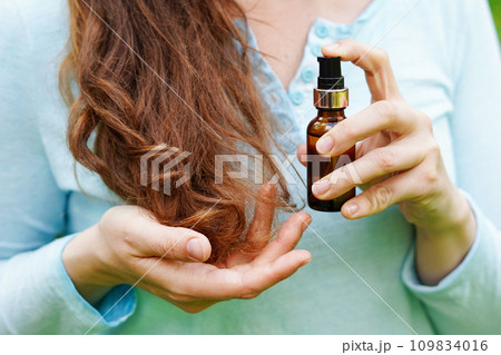 Young woman applying natural organic essential oil on hair. spa and beauty rituals. Skin care 109834016