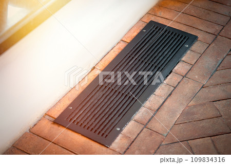 Hidden heating radiator built into the floor. Convector grille under the window Hidden heating radiator built into the floor. Convector grille under the window 109834316