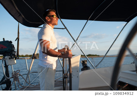 Short-haired confident mature man sailing on a yacht Short-haired confident mature man sailing on a yacht 109834912