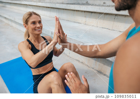 Fit woman doing sit-up with with personal trainer. 109835011