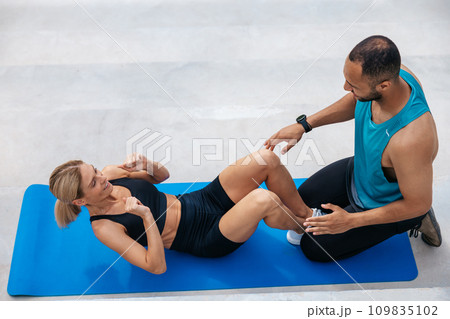 Woman with blonde hair in excellent shape doing sit-ups with her boyfriend, Woman with blonde hair in excellent shape doing sit-ups with her boyfriend, 109835102