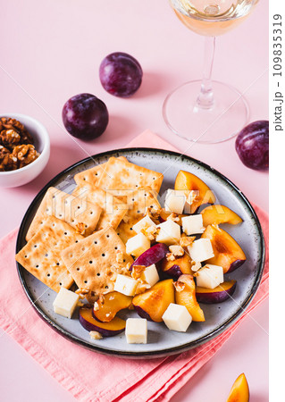 Dinner for girls, biscuits, cheese, plums and walnuts on a plate on the table vertical view 109835319