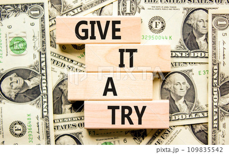 Give it a try symbol. Concept word Give it a try on beautiful wooden block. Dollar bills. Beautiful background from dollar bills. Business give it a try concept. Copy space. 109835542