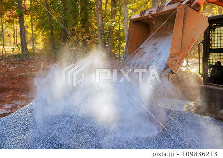 Using tractor, prepare basis for new road by laying crushed stone gravel which has been filled 109836213