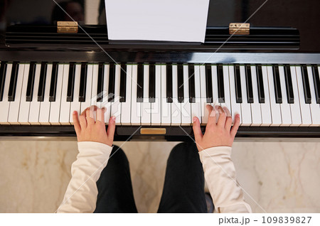 Top view of a child student, future musician pianist touching the white keys with his fingers, playing grand piano 109839827