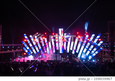 In heart of night a concert festival unfolds with enthusiastic crowd their admiration and cheers fill the air. lens flare adds to the excitement as people have a great time at this lively music event. 109839967