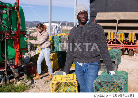 African american man carrying empty plastic boxes at farm 109841891