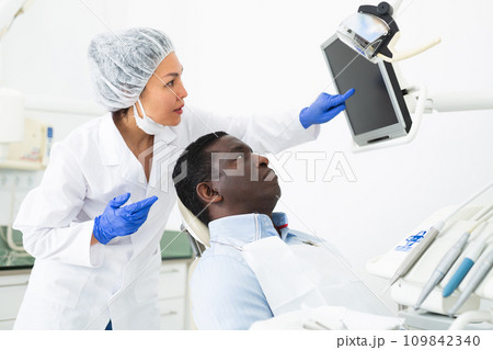 Woman dentist pointing at display to show information to patient 109842340