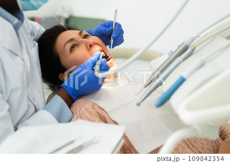 Female patient sitting with open mouth at dental office during treatment Female patient sitting with open mouth at dental office during treatment 109842354