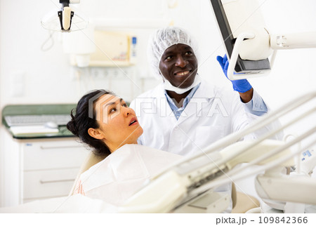 Woman sitting on dental chair, male dentist pointing at display 109842366