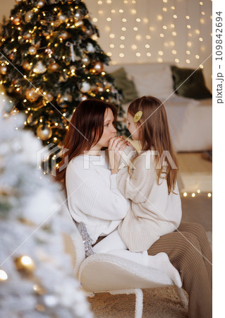 Mother and daughter enjoying cozy Christmas evening. Mother and daughter enjoying cozy Christmas evening. 109842694
