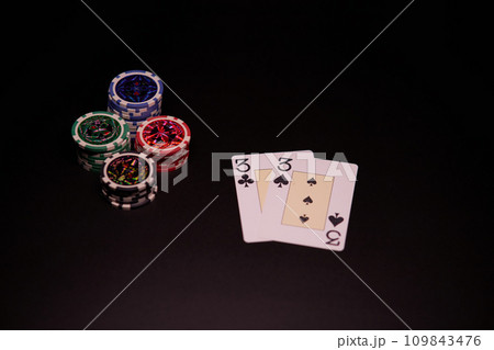 The interior of the casino. Playing cards close-up at the poker table combination of cards a pair of threes. 109843476