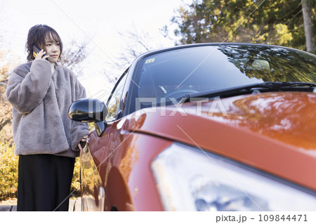 駐車場に車を止めてスマホで連絡を取る若い女性 車の故障イメージ 駐車場に車を止めてスマホで連絡を取る若い女性 車の故障イメージ 109844471