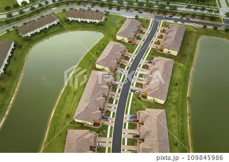 Aerial view of tightly packed homes in Florida closed living clubs with lake water in the middle. Family houses as example of real estate development in american suburbs 109845986