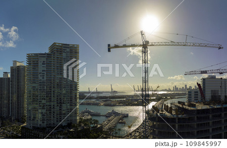 New construction site of developing residense in american urban area. Industrial tower lifting cranes in Miami, Florida. Concept of housing growth in the USA New construction site of developing residense in american urban area. Industrial tower lifting cranes in Miami, Florida. Concept of housing growth in the USA 109845997