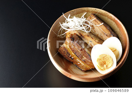 白髪葱乗せ厚切り炙りチャーシューとゆで卵を黒背景で俯瞰撮影 109846589