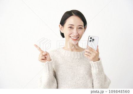 スマホを持って左側を指差す中年女性　白背景 109848560