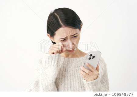 スマホを見て泣く中年女性　白背景 109848577
