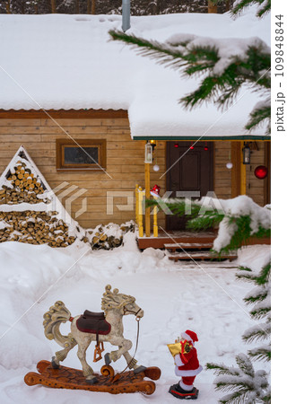 Toy Santa Claus with a wooden rocking horse on the background of a wooden house 109848844