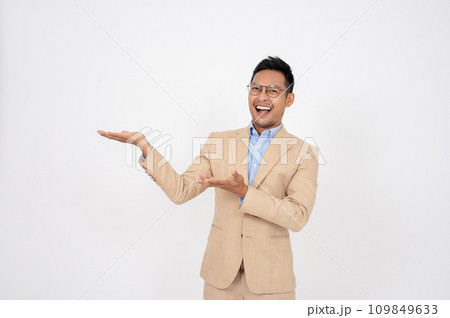 A handsome Asian businessman is opening his palms aside at an empty space on an isolated background. A handsome Asian businessman is opening his palms aside at an empty space on an isolated background. 109849633