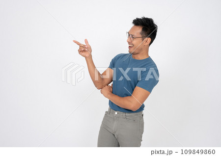 A handsome Asian man is pointing his finger aside at an empty space on an isolated white background. A handsome Asian man is pointing his finger aside at an empty space on an isolated white background. 109849860