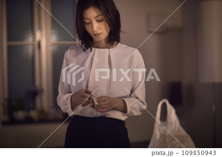 ジャケットを脱いで腕時計を外すビジネスウーマンのナイトルーティーン ジャケットを脱いで腕時計を外すビジネスウーマンのナイトルーティーン 109850943