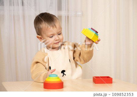 A two-year-old boy plays with wooden toys to develop logic and motor skills 109852353