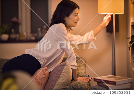 ジャケットを脱いでスタンドの電気をつけるビジネスウーマンのナイトルーティーン ジャケットを脱いでスタンドの電気をつけるビジネスウーマンのナイトルーティーン 109852651