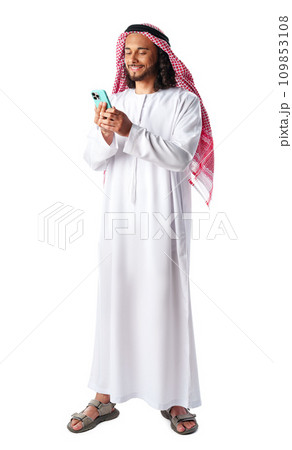 Young Arab man in traditional dress thobe using smartphone at white background Young Arab man in traditional dress thobe using smartphone at white background 109853108