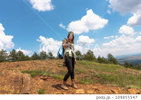 Tourist girl taking photos with smartphone while Hiking at the top of the mountain Tourist girl taking photos with smartphone while Hiking at the top of the mountain 109855547
