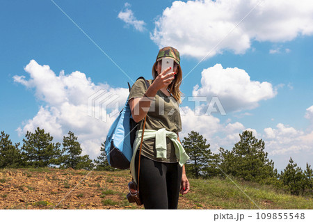 Tourist girl taking photos with smartphone while Hiking at the top of the mountain 109855548
