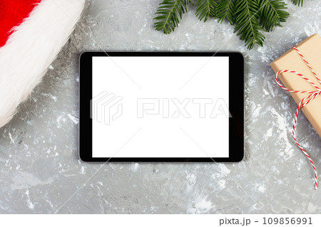 Tablet on Christmas background with santa hat and gift box. New Year holiday 109856991