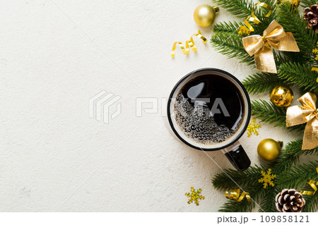 Delicious fresh festive morning coffee in a ceramic cup with little wrapped gifts, ornament and xmas toy. Cup of coffee and new year toys 109858121