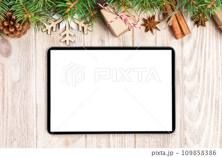 Digital tablet mock up with rustic Christmas wood background decorations for app presentation. top view with copy space Digital tablet mock up with rustic Christmas wood background decorations for app presentation. top view with copy space 109858386