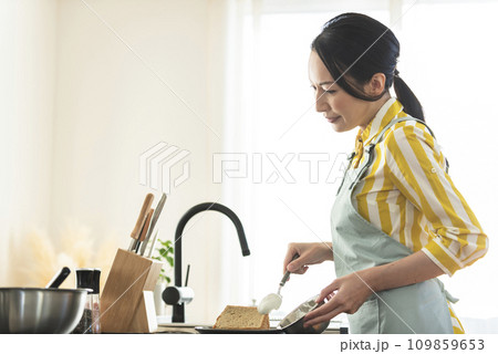 シフォンケーキに生クリームを盛り付けする女性 109859653