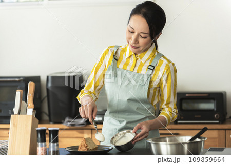 シフォンケーキに生クリームを盛り付けする女性 109859664