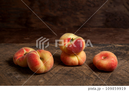 Several saturn peaches or flat peaches on wooden background.. 109859919