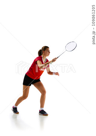 Beauty and prowess. Portrait of young and attractive badminton player in motion, training diligently against white background. Beauty and prowess. Portrait of young and attractive badminton player in motion, training diligently against white background. 109861205