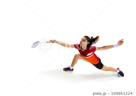 Dynamic portrait of professional female badminton player engaged in lively training session against white studio background. Dynamic portrait of professional female badminton player engaged in lively training session against white studio background. 109861224