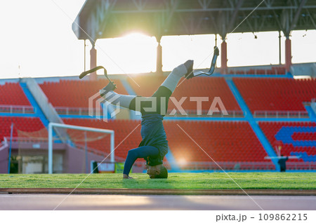 Sport man athlete prosthesis legs push head on grass field and separate legs in the stadium with soft light in evening. Sport man athlete prosthesis legs push head on grass field and separate legs in the stadium with soft light in evening. 109862215