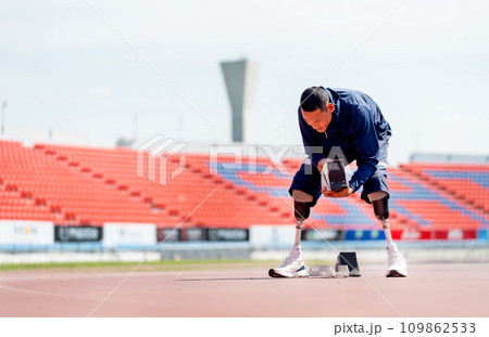 Wide shot of sport man athlete with a prosthesis on his leg prepare of the running equipment on the track at the stadium. Sport concept. 109862533